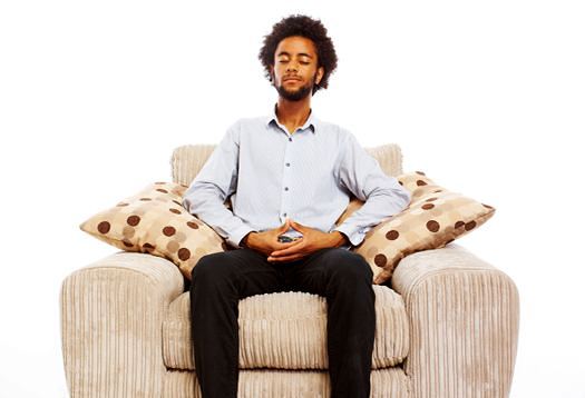 content young man sitting meditating in comfy chair